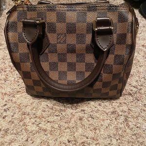 Brown checkered fashion bag with crossbody strap. Red interior.